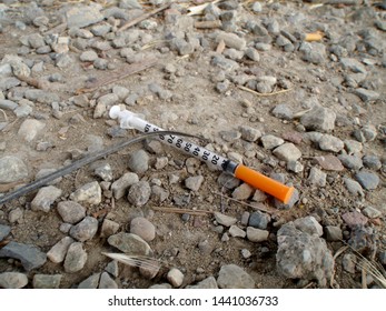 Used Drug Needle On The Ground Among Rocks And Dirt