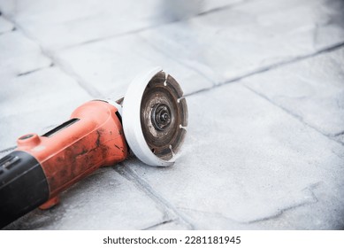 used electrical angle grinder on gray cement floor, famous construction hand tool machine