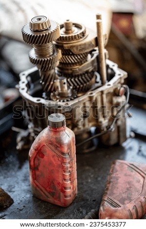 Used engine oil gallon and disassembled car automatic transmission gear part or gearbox on workbench in auto repair shop. Fix and maintenance vehicle part service in the garage