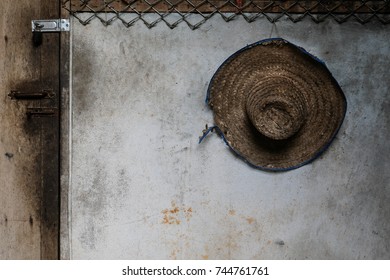 Used farmer straw hat hung on a wall, beautiful vintage background