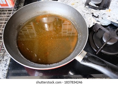 Used frying pan with oil on the stove. Selective focus. Contaminant cooking oil, old or used product in cooking pan. It can be reused for bio-diesel but not to reused  for cook. Causes of Carcinogenic