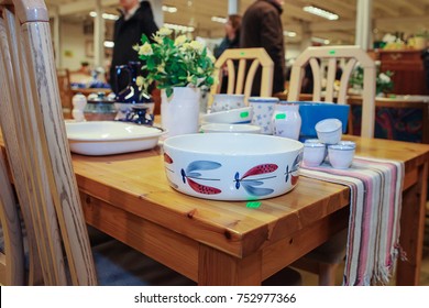 Used Household Items Are Sold In A Thrift Store. Shoppers Are Out Of Focus In The Background.