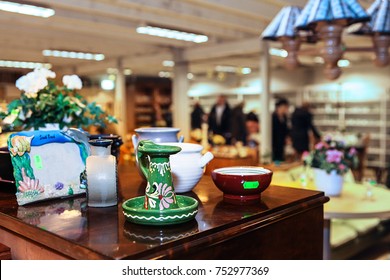 Used Household Items Are Sold In A Thrift Store. Shoppers Are Out Of Focus In The Background.