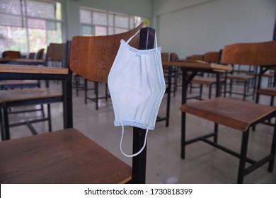 The used medical face mask hangs on the wood lecture chairs in the empty classroom. Concept during the Coronavirus Disease COVID-19 outbreak and pandemic in the 2020s. Back to school concept. - Powered by Shutterstock