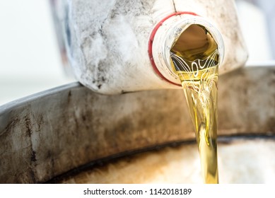 Used Motor Vehicle Car Engine Oil Being Poured From Oil Pan To Disposal Container.