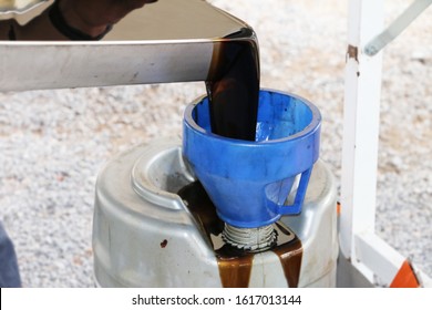 Used Motor Vehicle Car Engine Oil Being Poured From Oil Pan To Disposal Container.