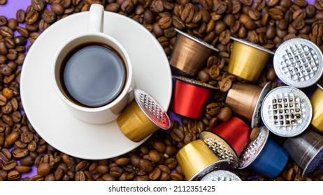 Used Nespresso Capsules On Coffee Beans, The Problem Of Contamination Of Coffee Capsules. A White Cup Of Coffee And Used Nespresso Capsules.