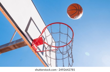 Used orange basketball with basket in background. Basketball street court stock photo