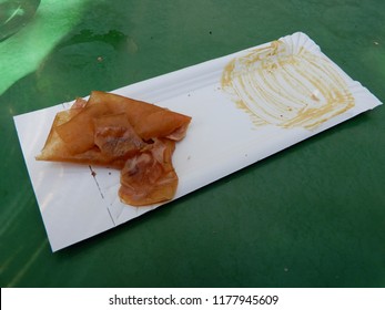 A Used Paper Plate With A Rest Of The Sausage And The Bread With Mustard