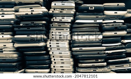 Used phones stacked on top of each other. Background of damaged mobile phones. A bunch of broken smartphones. Equipment repair and maintenance services. Parts for assembly.