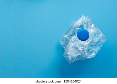 Used plastic bottles crushed and crumpled against on the blue background. Recycling concept