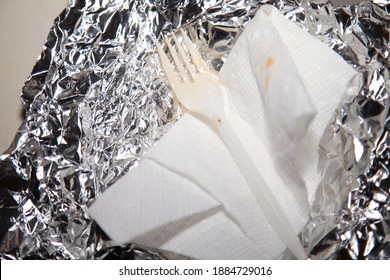 Used Plastic Fork On A Used Paper Towel On Tin Foil On A White Surface