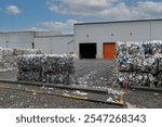 Used plastic milk bottles and cartons that have been bundled into stacked bales and ready for recycling at an industrial plastic waste recycling plant