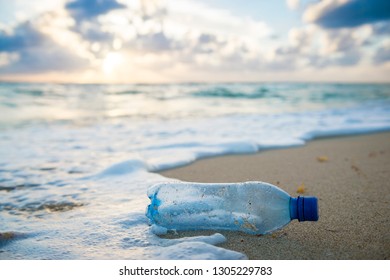 Used plastic water bottle washed up on the shore of a tropical beach, highlighting the worldwide crisis of plastic pollution on even the most remote islands - Shutterstock ID 1305229783