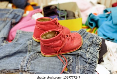 Used Red Shoes For Children In A Thrift Shop Between Other Used Clothes - Selective Focus