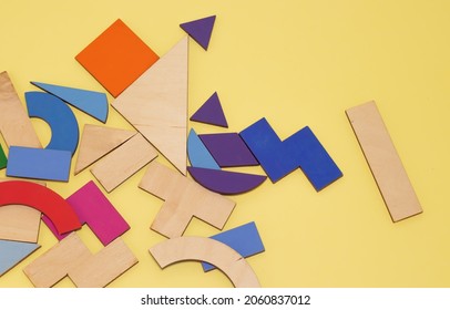 used tangram game pieces placed chaotic on a wooden board.colorful puzzle pieces. green, violet, pink, orange. iq games, intelligence and educational jigsaw game