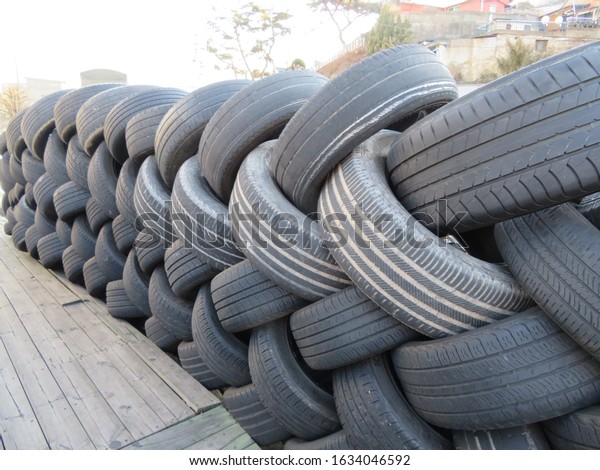 Used tires stacked in an\
interlocking pattern next to an auto garage parking lot in Seoul,\
Korea