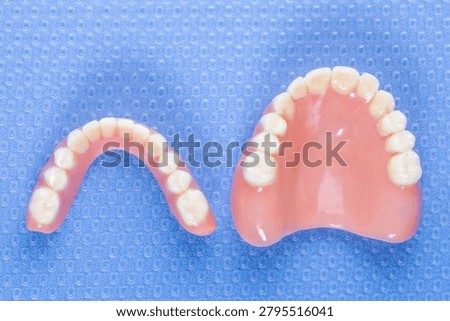 Used upper and lower dentures placed on a blue dental mat photographed from above showing dental prosthetics in clinical environment