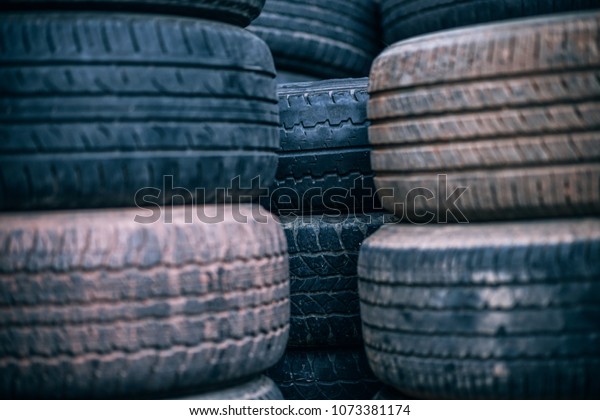 Used vehicle tires are stacked in an auto\
shop. Dusty tires are stacked in\
piles.\
