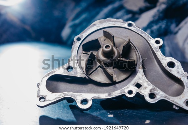 Used water pump for car engine cooling system\
on blue background.