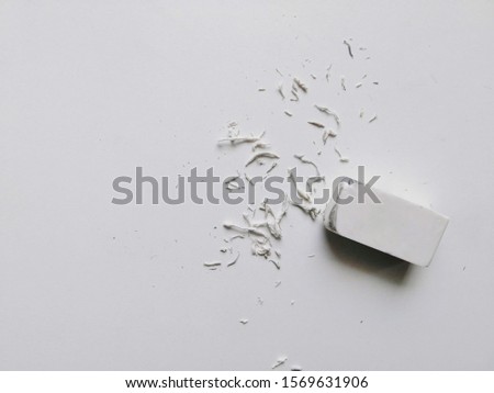 Used white eraser with eraser shavings on white table 