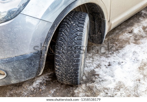 Used winter studded\
car wheel on the snow