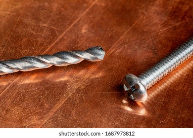 A  Used And Worn Drill Bit And A Screw Waiting To Be Used Again, Resting On A Worn And Oxidized Copper Work Surface.  Shot For Copy Writing With Plenty Of Negative Space On The Copper Surface.