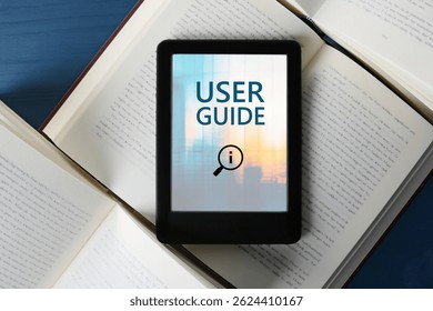 User Guide document open in e-book device and different books on blue wooden table, top view