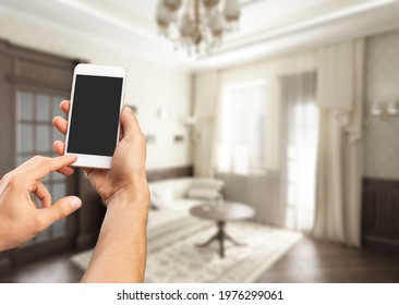 User hands controlling electronic objects in the modern apartment on the cellphone
