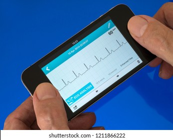 User Holding Portable Handheld ECG EKG Heart Monitor App Running On Mobile Phone With Trace Showing Normal Sinus Heart Rhythm.