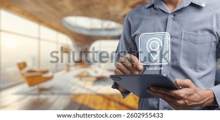 A user interacts with a location icon on a tablet in a stylish interior setting, highlighting modern technology in a contemporary workspace. The image captures the blend of digital and physical realms