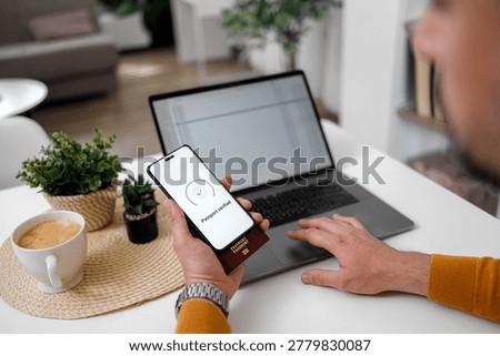 User scans passport with smartphone while sitting at desk with laptop open and coffee beside. The task focuses on verification.