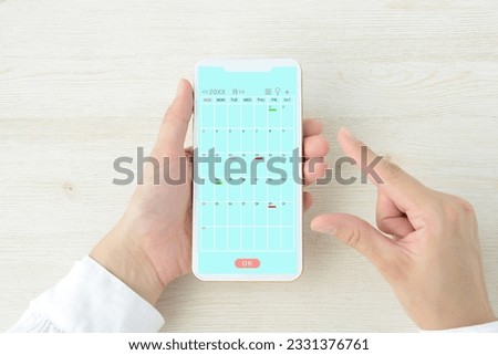 User's hands and smartphone with schedule calendar screen