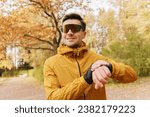 Uses a fitness app and watches and sports glasses for running, the trainer does the exercise.  The athlete is active and healthy in winter in the park. A confident and hardy man.