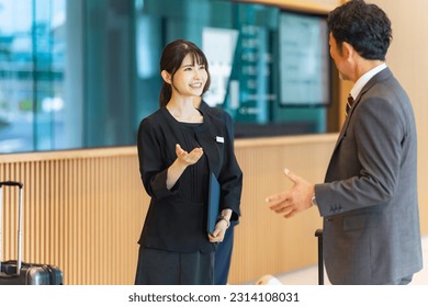 An usher woman serving tourists at the front desk. Hotelier.