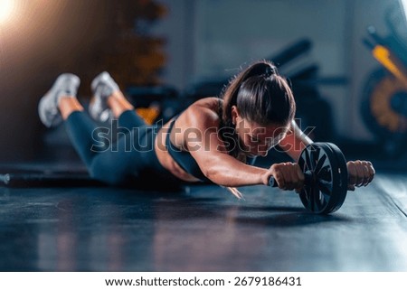 Using an ab weel for strength training in the gym, a woman improves power and streinght abs. This effective workout supports health goals and enhances vitality with dynamic resistance.