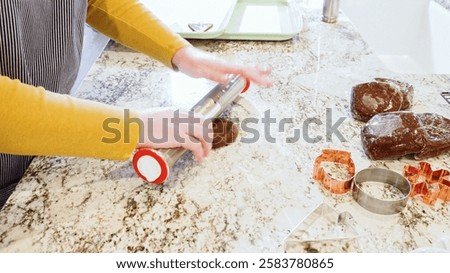Using an adjustable rolling pin to roll out gingerbread cookie dough on the elegant marble counter in a modern kitchen, getting ready for festive holiday baking.