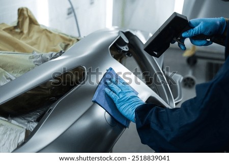 Using anti static gun to prevent damages and remove dust before covering car with paint. Mechanic is working with anti static gun to prepare metal for paintwork