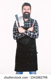 Using a barbecue set. Confident grill cook. Bearded man holding grill gripper tools. Hipster in apron with metal utensils for barbecue grill. Preparing food on grill.