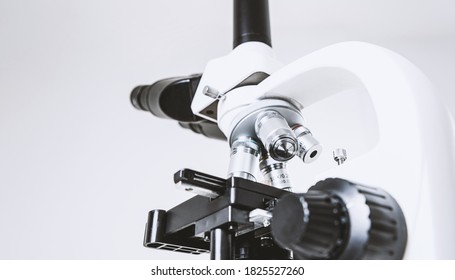 Using a biological microscope. Close-up of the microscope lens. Scientific research concept, using a microscope. Medical examinations, searching for bacteria, diseases, blood tests.