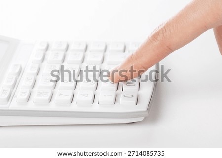 Using a calculator to input numbers for a simple calculation task at a desk