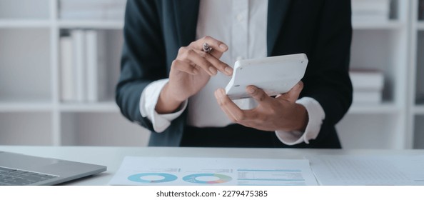 Using calculator and laptop, Close up hands of asian bookkeeper female working with stack of papers and balance sheet with bureaucracy hardworking in office desk.