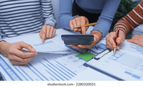 Using calculator, small business accounting team meeting three asian people with salary monthly charts data, basic business accounting and bookkeeping concept.