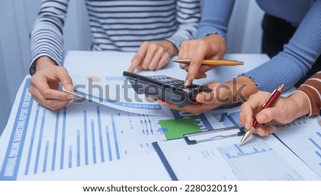 Using calculator, small business accounting team meeting three asian people with salary monthly charts data, basic business accounting and bookkeeping concept.