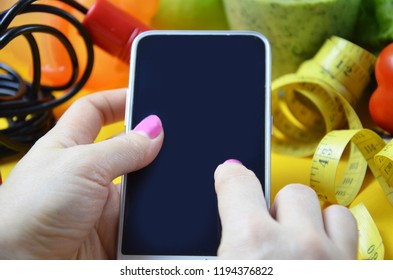 using calorie counter application on her smartphone. fruits and vegetables of different colors, green smoothies. diet vegetarian is a healthy low-calorie food. notebook with a diet plan