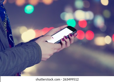 Using cellphone at night - with defocused city lights in the background.