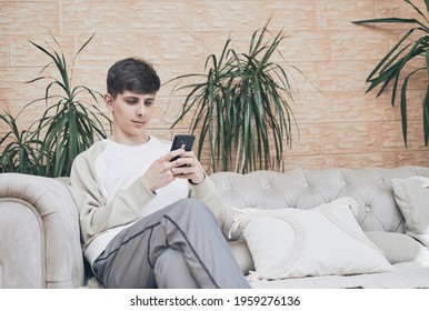 using cellphone on sofa in apartment, an using mobile phone at home