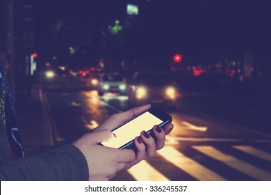 Using cellphone outdoors - with defocused city traffic. - Powered by Shutterstock