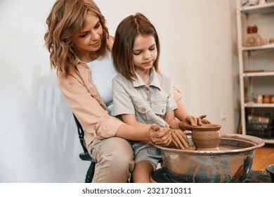 Using clay to create the pot. Mother with little girl learning pottery in the workshop. - Powered by Shutterstock - Get 15% off with code: PIKWIZARD15