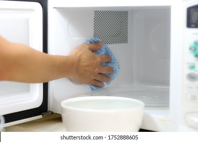 Using A Cloth Or A Rag To Clean A Microwave Oven In Kitchen Room